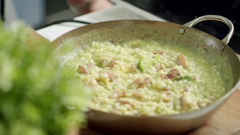 crop chef stirring hot risotto in pan