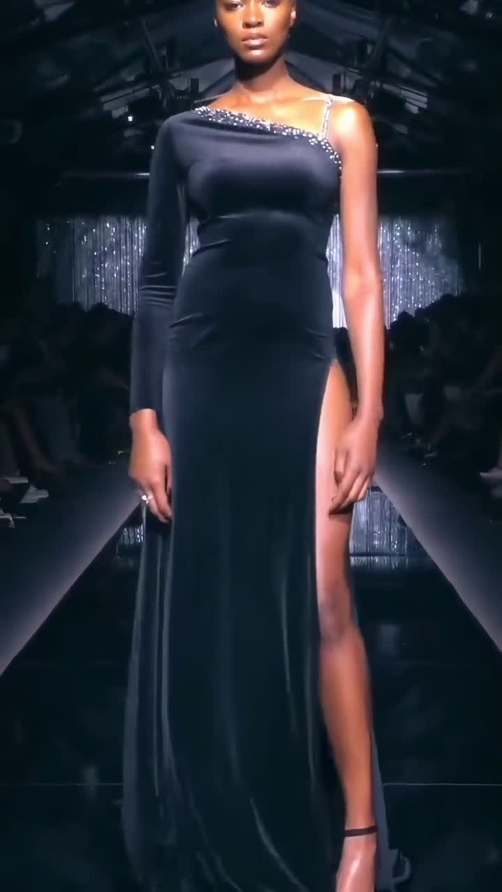 Lavvinkelvideo af en model i en elegant, strømlinet kjole på en glitrende catwalk.