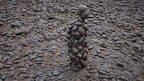stone figure made of pebbles standing on a pebble beach representing balance, harmony, and connection with nature in a serene outdoor setting