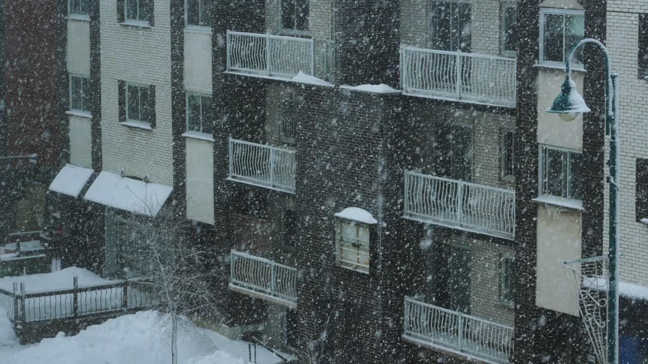 도시의 아파트 건물 밖에 눈이 내리는 겨울 눈보라
