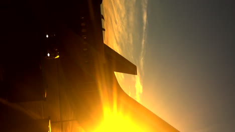 Sideways-view-of-the-sun-creeping-from-behind-the-tail-of-an-airplane-on-the-tarmac-at-the-airport