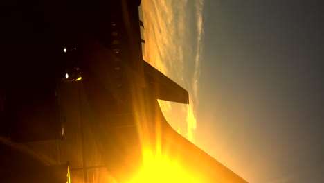 vista lateral del sol que se arrastra desde detrás de la cola de un avión en la pista del aeropuerto