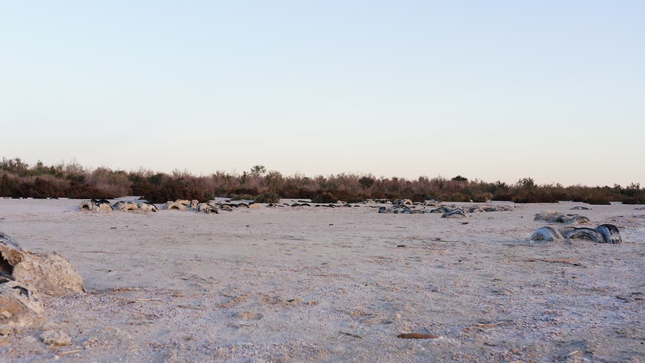 Flygfoto i låg vinkel av en väderbiten träbänk som står på de vita saltbelagda stränderna vid ökensjön Salton Sea
