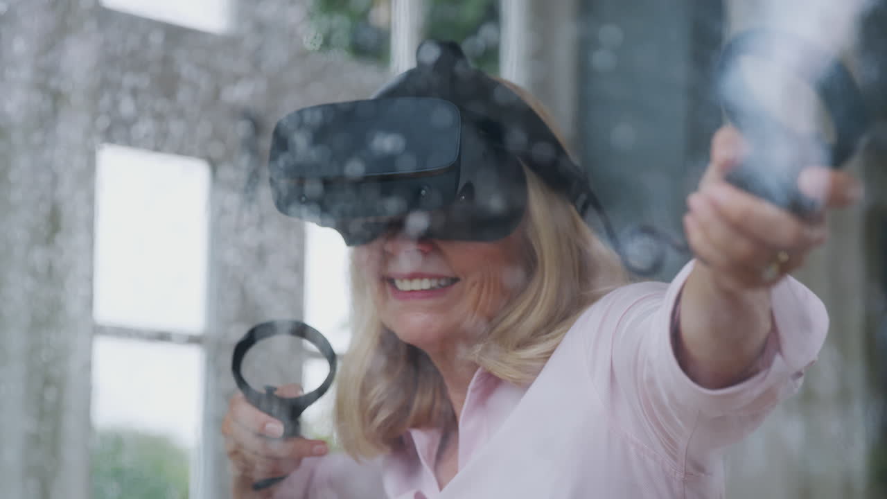 Vista dalla finestra di una donna matura che indossa un visore per la realtà virtuale e tiene in mano controller di gioco.