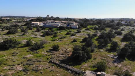 Tiro-De-Drone-De-Arbustos-En-Un-Campo-Por-Una-Pequeña-Torre-En-Ibiza