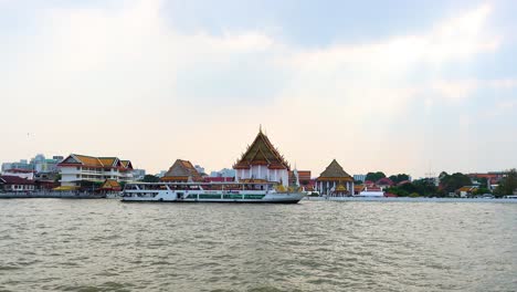 a boat travels past a riverside temple