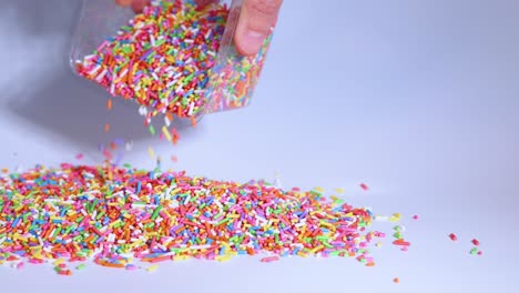 hand pouring sprinkles from container onto surface