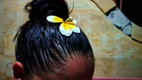 a bathing, dark-haired lady with a yellow lotus flower in her hair
