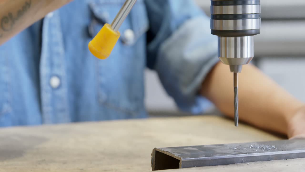 плотник, использующий вертикальную буровую машину в мастерской 4k