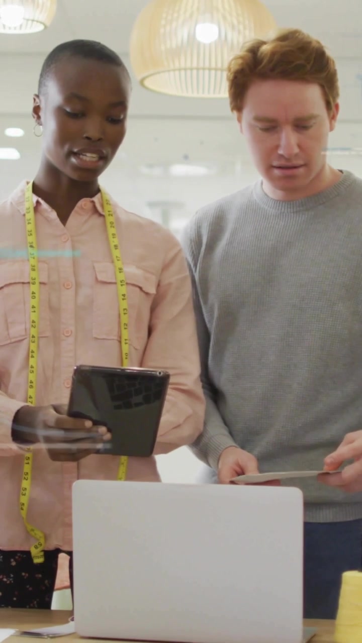 Vertical video: Woman tapping tablet man holding tile blue overlay aligning data reviewing design