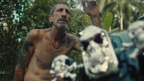 man smoking a cigarette near a motorcycle