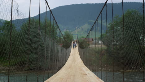 tourists running river bridge in mountains. hikers having fun together on nature