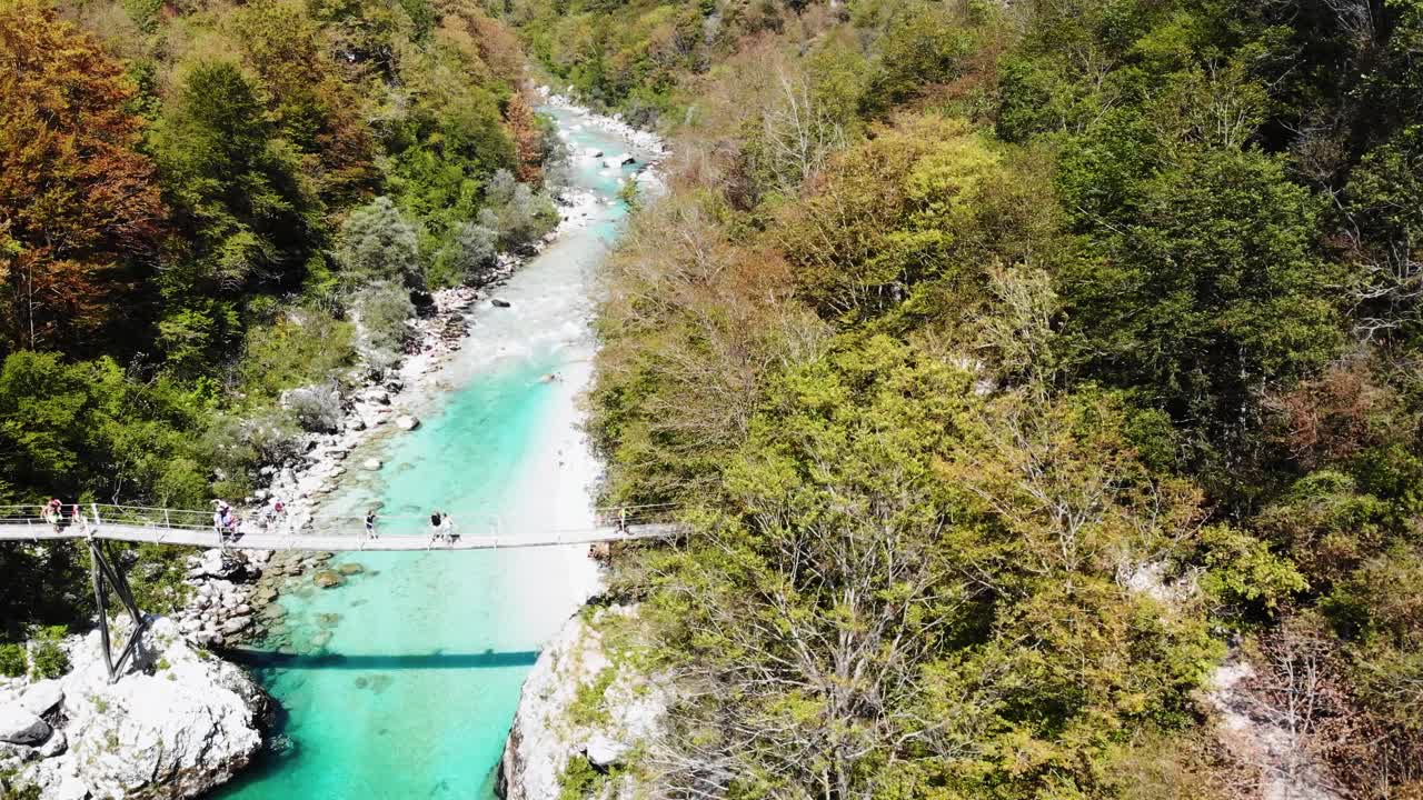 Aerial View of People Walking on a Suspension Bridge over a Turquoise River in Slovenia