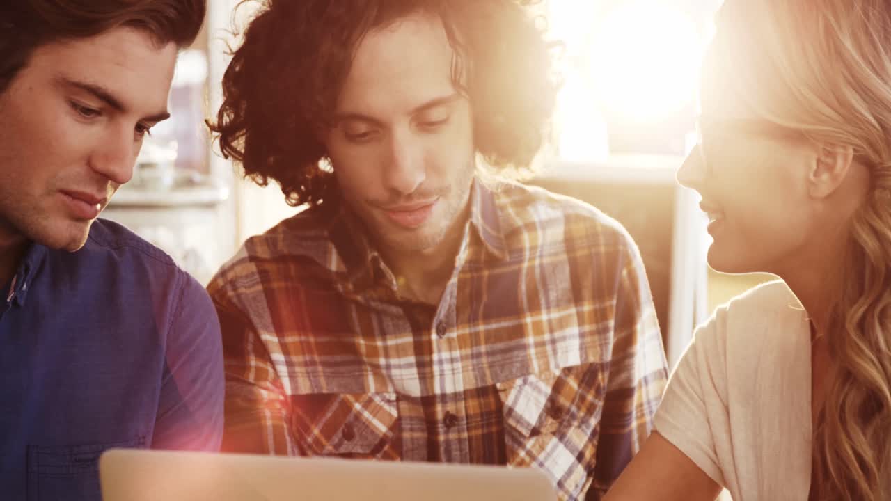 amigos usando computadora portátil mientras toman un café
