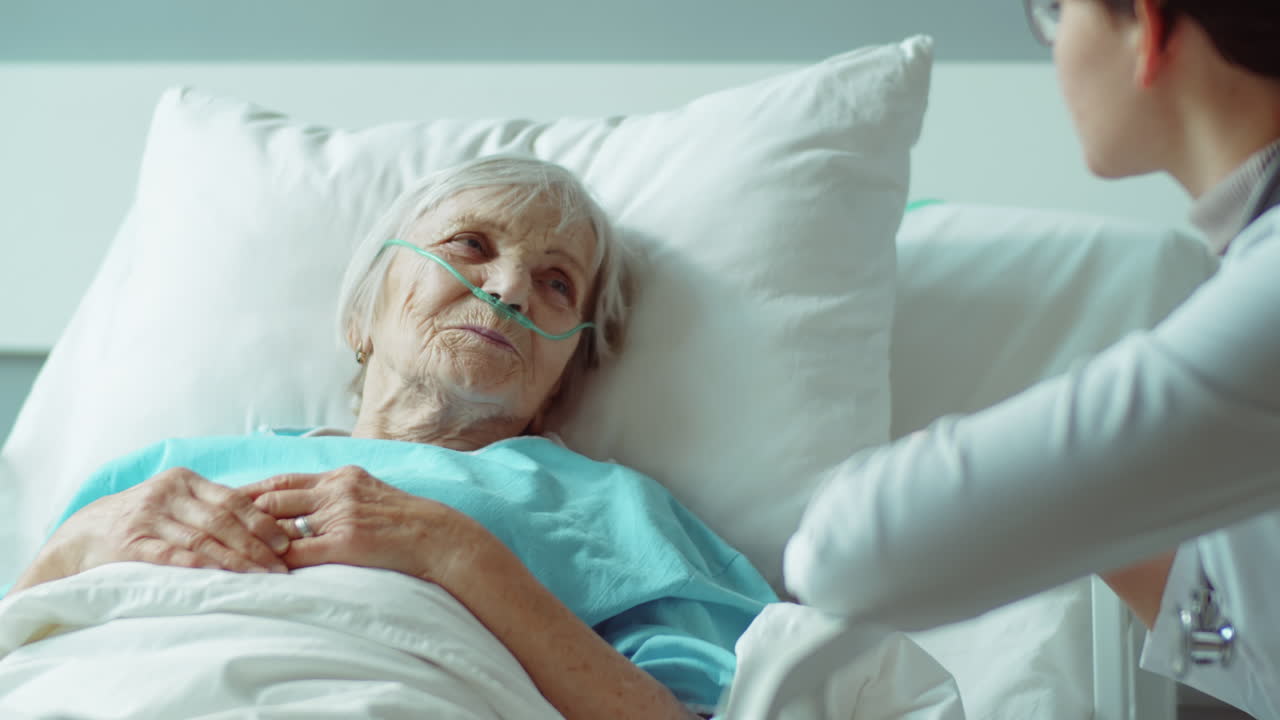 Donna anziana sdraiata su un letto d'ospedale che parla con il medico