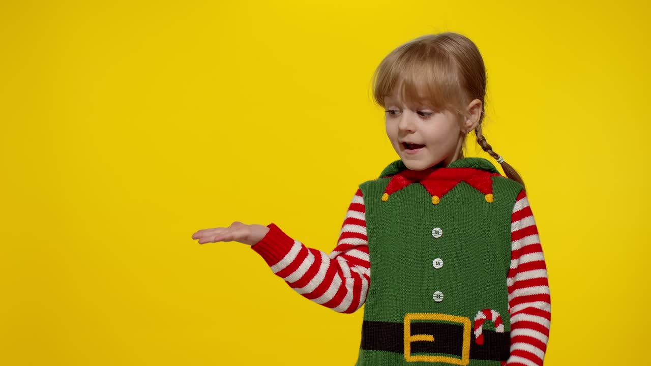 niña en el disfraz de santa elf ayudante señala los dedos en el espacio en blanco muestra área de publicidad