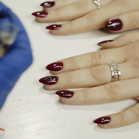 manicurist applying red nail varnish. rhinestones on nails square video