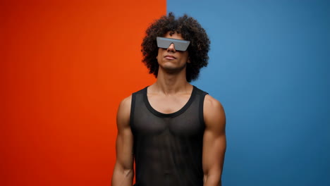 stylish man with curly hair and futuristic sunglasses on a two-tone background