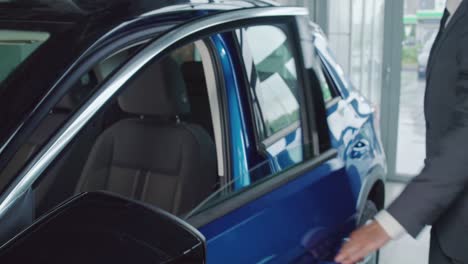 un hombre de negocios feliz probando un coche en una sala de exhibición antes de comprarlo.