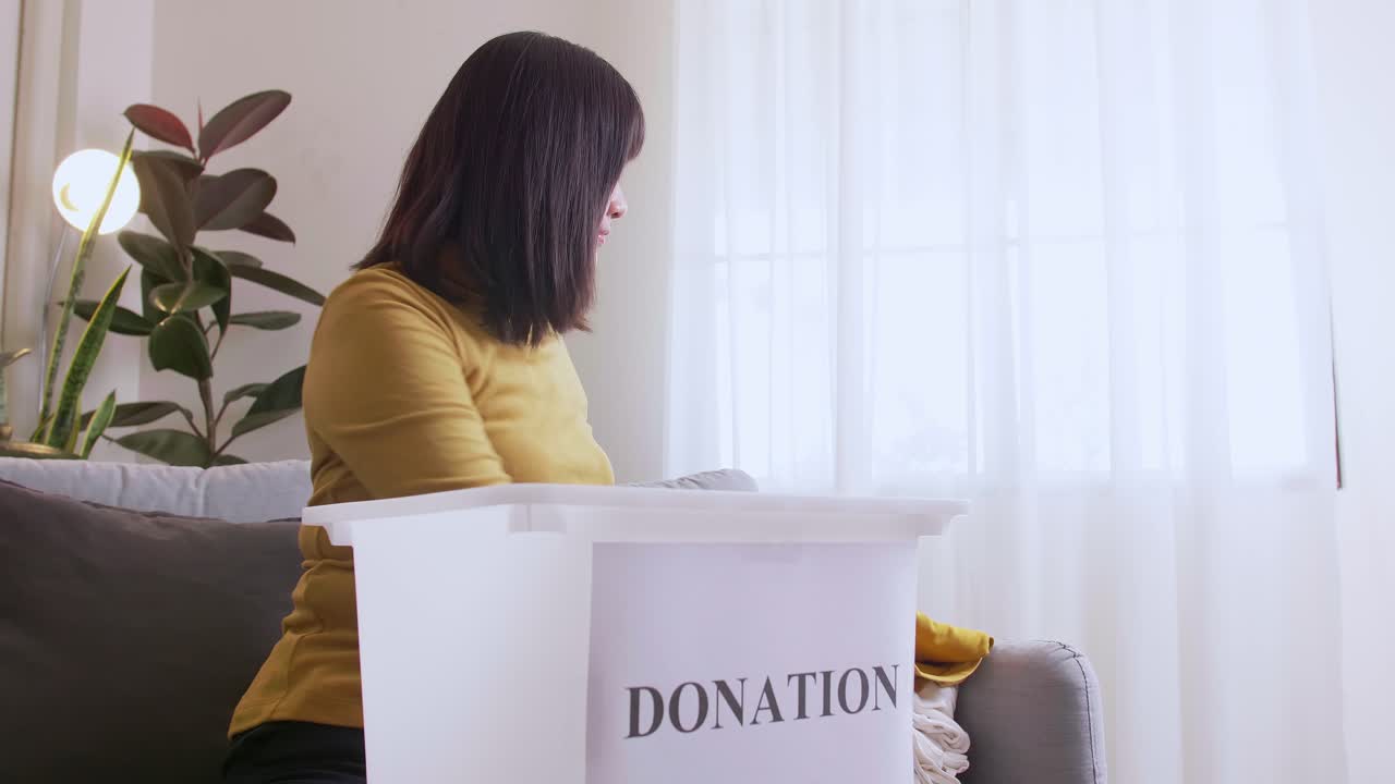 mujer seleccionando ropa para donar y poner en caja