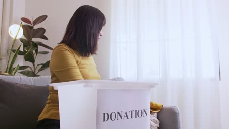 Woman-selecting-clothes-for-donation-and-putting-in-box