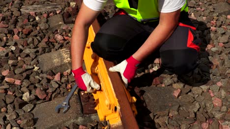 trabajador que fija una tuerca de tornillo en la vía ferroviaria