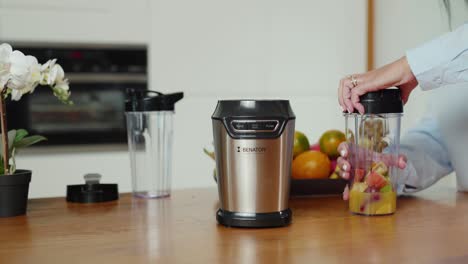 Hands-demonstrating-process-of-mounting-container-on-smoothie-mixer