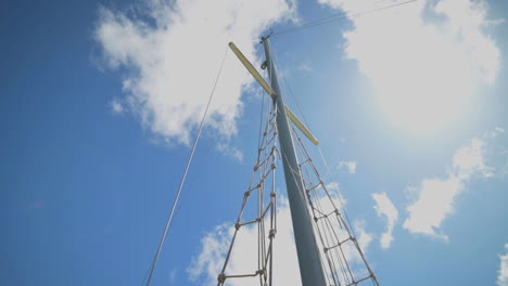 Un-Mástil-De-Barco-De-Vela-Contra-El-Hermoso-Cielo-Azul-Con-Nubes---Tiro-De-ángulo-Bajo