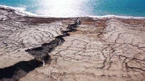 aerial view of cracked earth and sinkholes at the dead sea shoreline