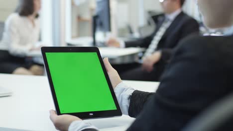 una trabajadora está sosteniendo una tableta con pantalla verde, genial para el uso de maquetas.