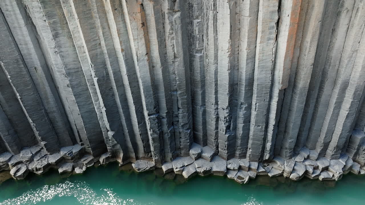 Canyon of basalt columns, cliff with turquoise river, in Iceland, aerial shot