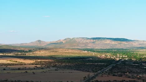 Panorámica-Aérea-Estableciendo-El-Campo-De-Aguascalientes-Bajo-La-Sombra-De-Las-Nubes,-Telón-De-Fondo-De-Montaña