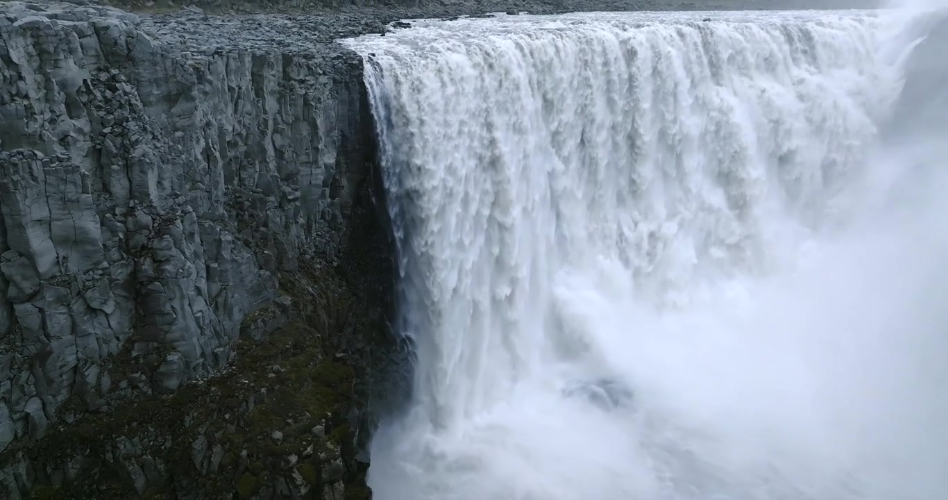Slow motion aerial camera pans upward revealing Dettifoss Waterfall on the Jokulsa a Fjollum in Jokulsargljufur Canyon, Vatnajokull National Park, Northeast Iceland, exposing cascading glacial water