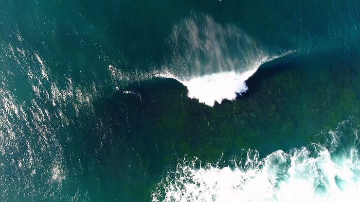 Top down of shifting water layers with surfers visible waiting in deep ocean lineup, aerial texture view