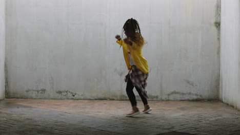 dancing woman young mixed race street dancer performing freestyle hip hop moves enjoying modern dance expression practicing in grungy warehouse wearing yellow jacket