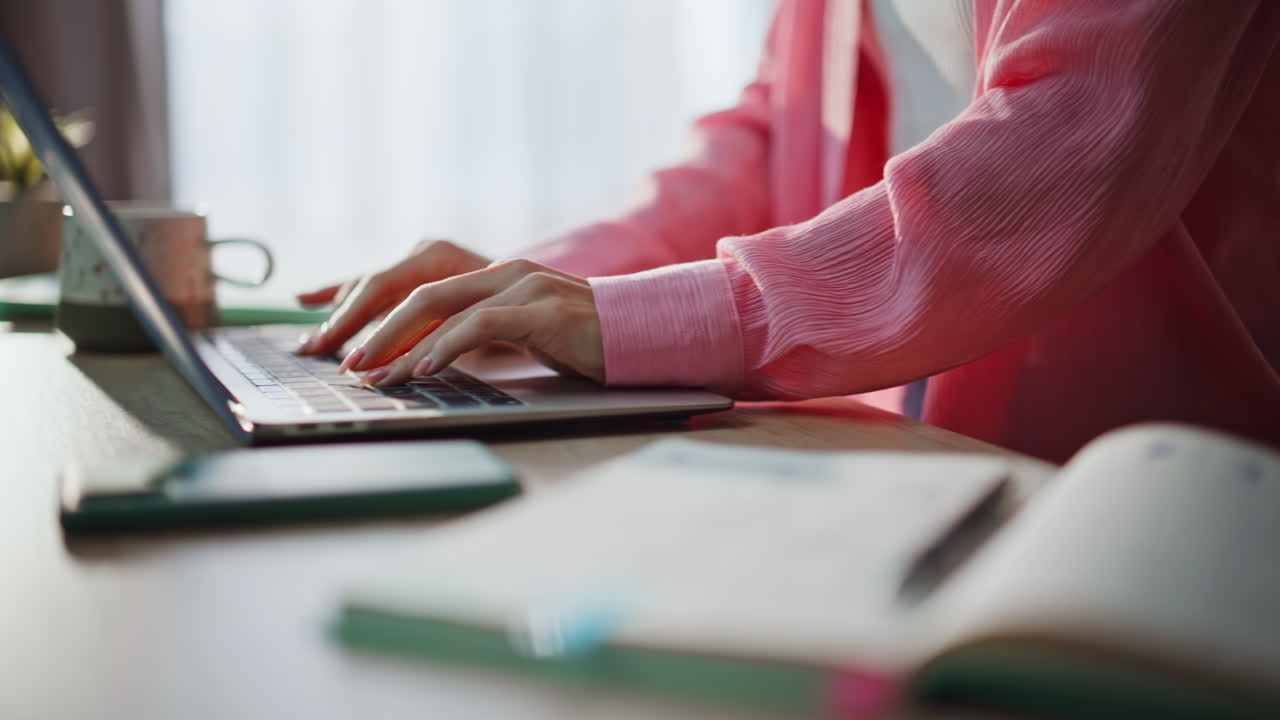 Close-up di una freelance che scrive su un quaderno mentre lavora al laptop. Donna che studia