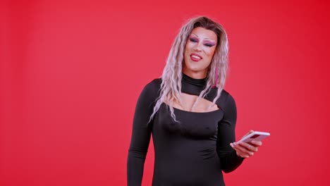drag queen posing and interacting with a smartphone on a red background