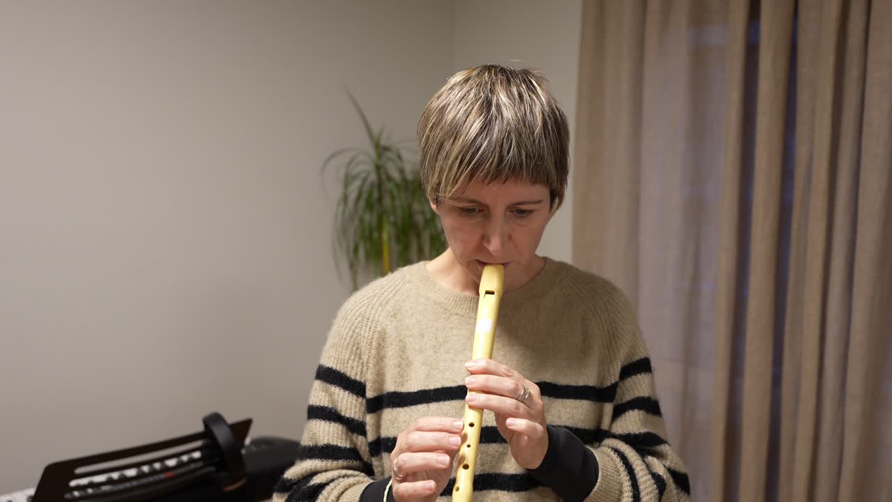 Donna che suona un flauto dolce in un ambiente interno