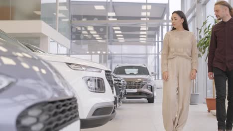 beautiful young couple at car showroom choosing a new car to buy.