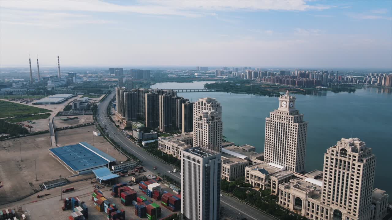 Aerial view of tall buildings and shipping containers by the riverside