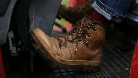 person driving tractor with leather boots