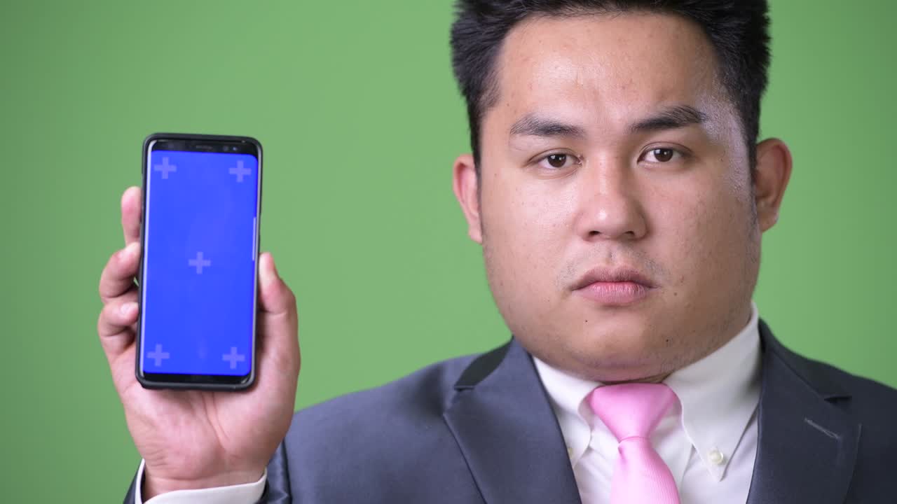 초록색 배경에 젊은 잘생긴 과체중 아시아 사업가