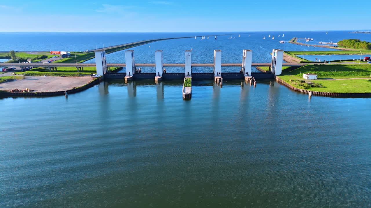 Distancing from the Houtrib sluices near Lelystad, the Netherlands. White sails on the blue waterscape at backdrop. Aerial view.