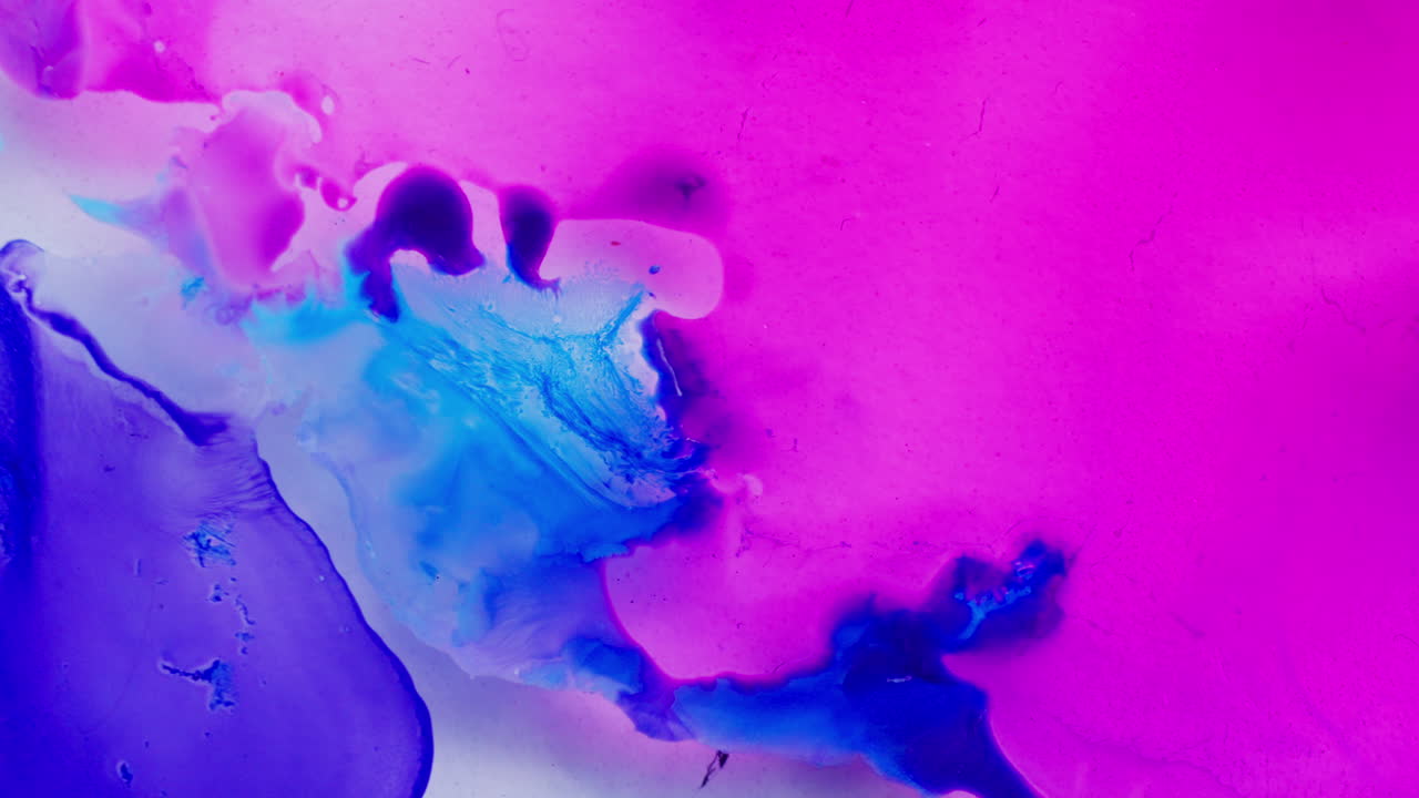 Mistura de tintas de cores diferentes em líquido. Tons de roxo, branco e azul.