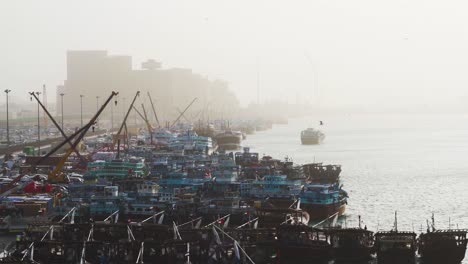 Dhow-Cargo-And-Fishing-Boats-Moored-At-Fishing-Port-On-A-Foggy-Morning-In-Dubai,-UAE