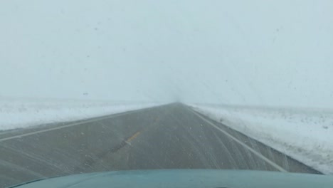 conducción invernal a lo largo de una carretera larga y vacía, en un paisaje helado, clima brumoso y nieve que cae