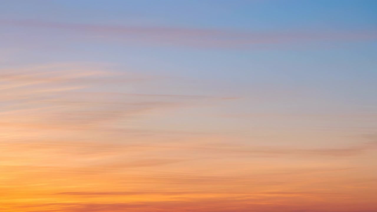 Wide, horizonless sky filled with a soft pastel sunrise gradient transitioning from warm orange and peach near the lower third to lavender and pale blue