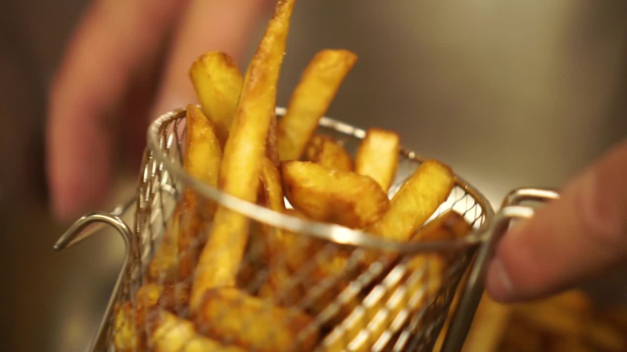 Close Up - Putting perfectly cooked crispy french fries into a metal basket