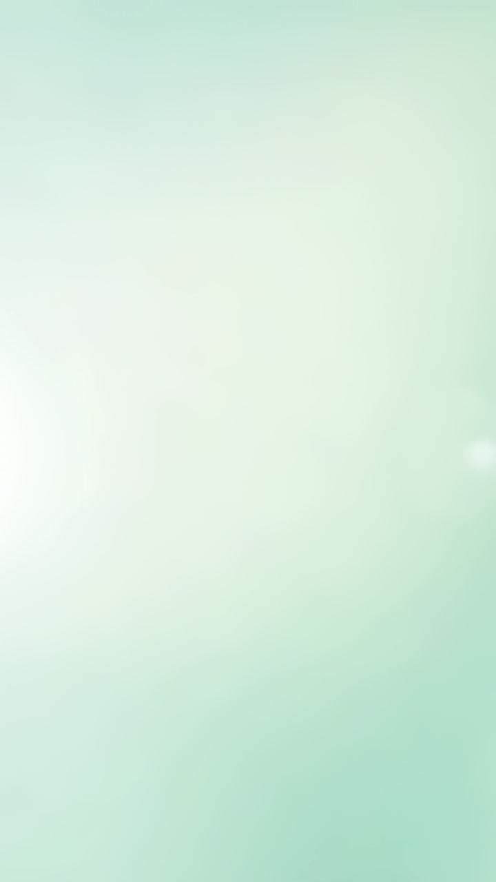 Vertical video: Appearing 3rd bokeh urging right flare growing on mint background left orb drifting