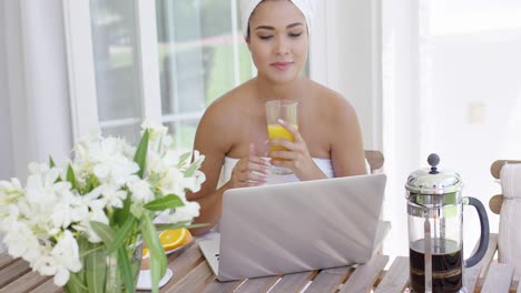 mujer en toalla con computadora portátil tomando el desayuno